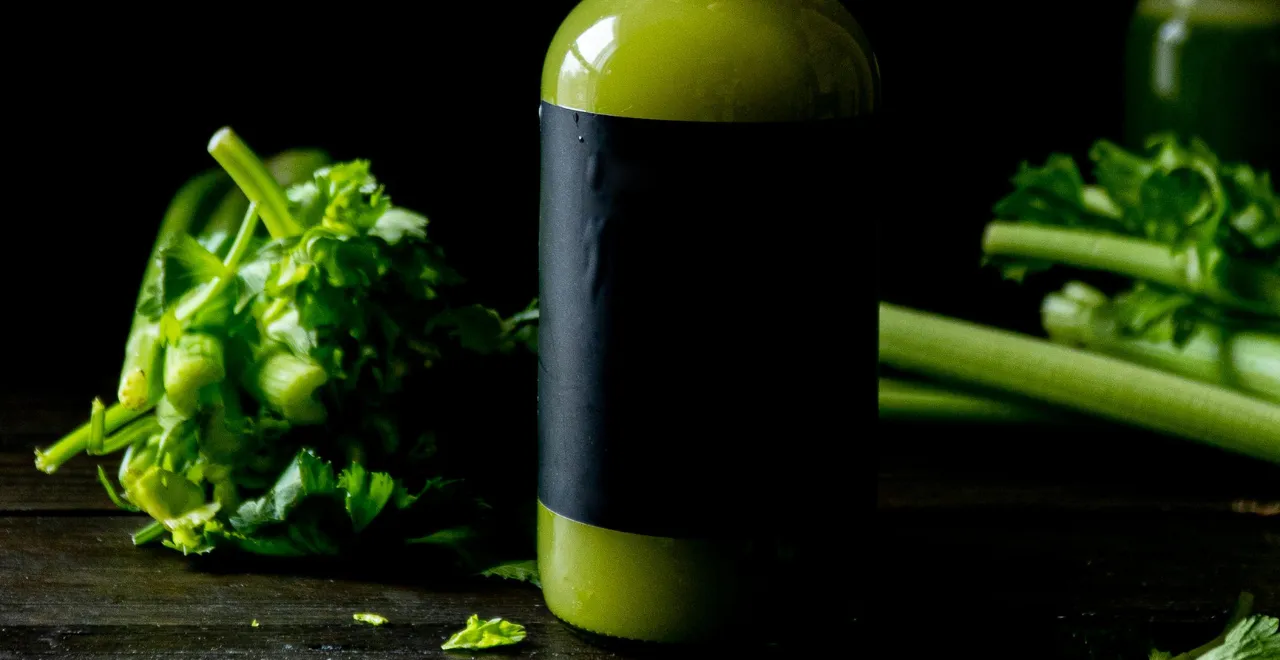 Céleri frais à côté d'un verre de jus vert